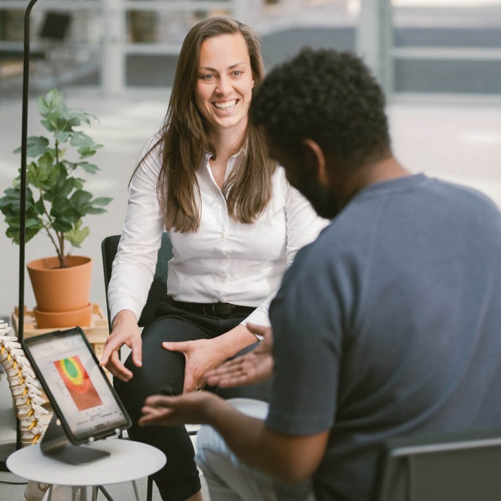 Twee mensen in gesprek bij tablet op tafel.